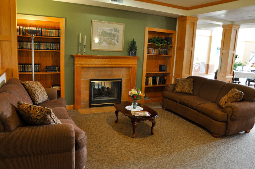 Cozy lounge area at Charter Senior Living of Madison, WI, featuring fireplace, bookshelves, and comfortable seating for resident relaxation and connection