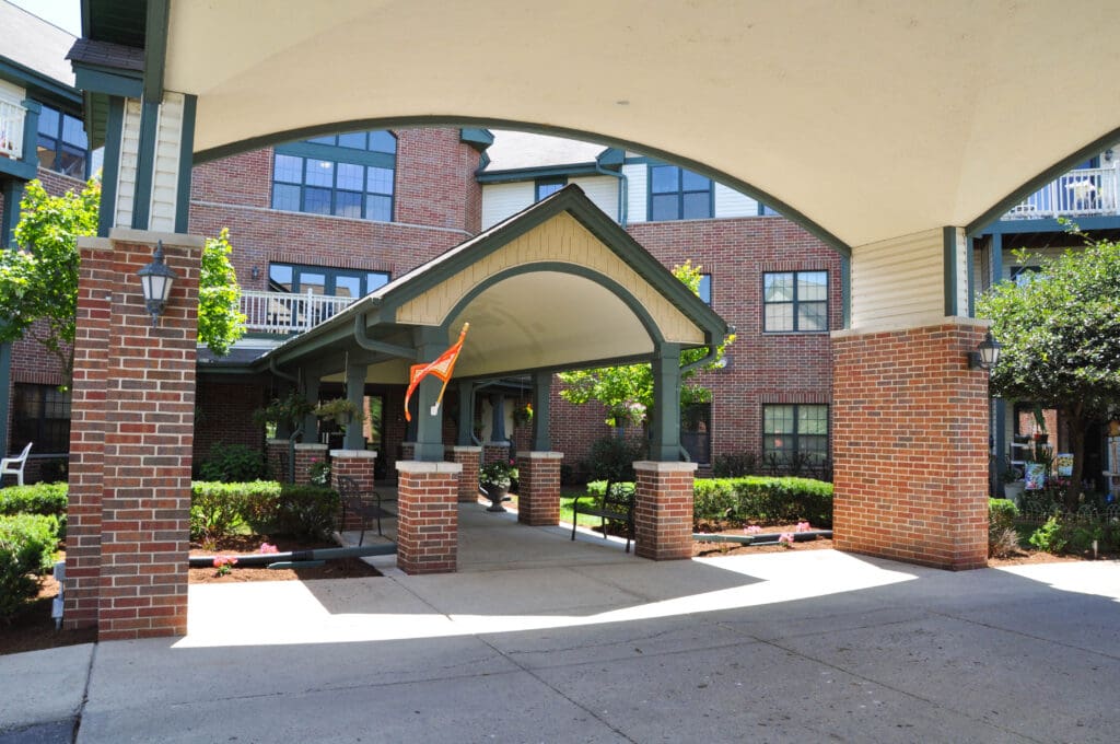 Covered main entrance at Charter Senior Living of Madison, WI, with brick exterior and landscaped garden welcoming residents and visitors