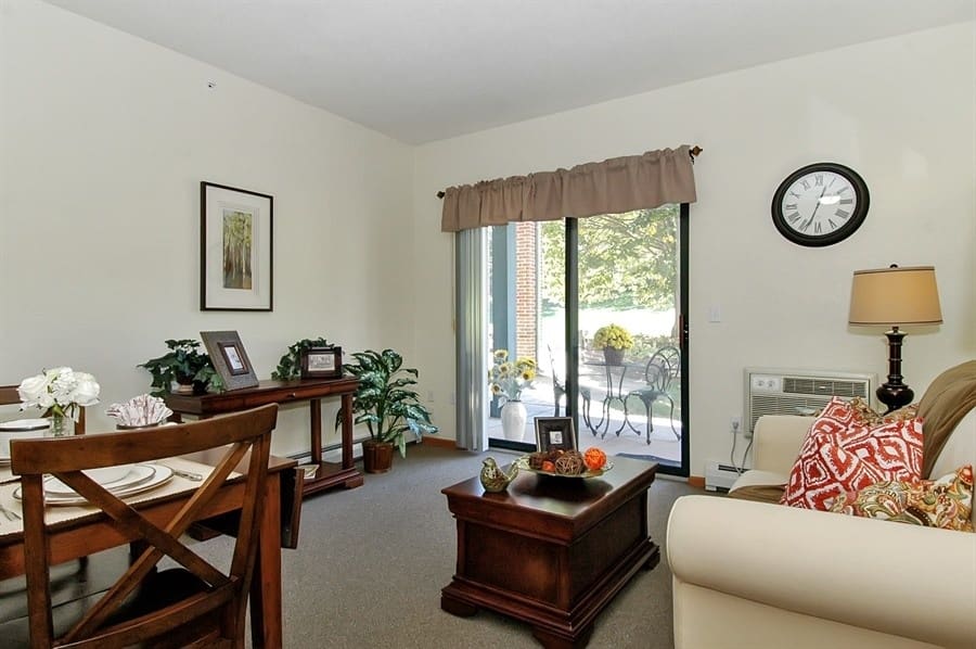 Senior apartment living room at Charter Senior Living of Madison, WI, with patio access, cozy seating, and elegant dining area.
