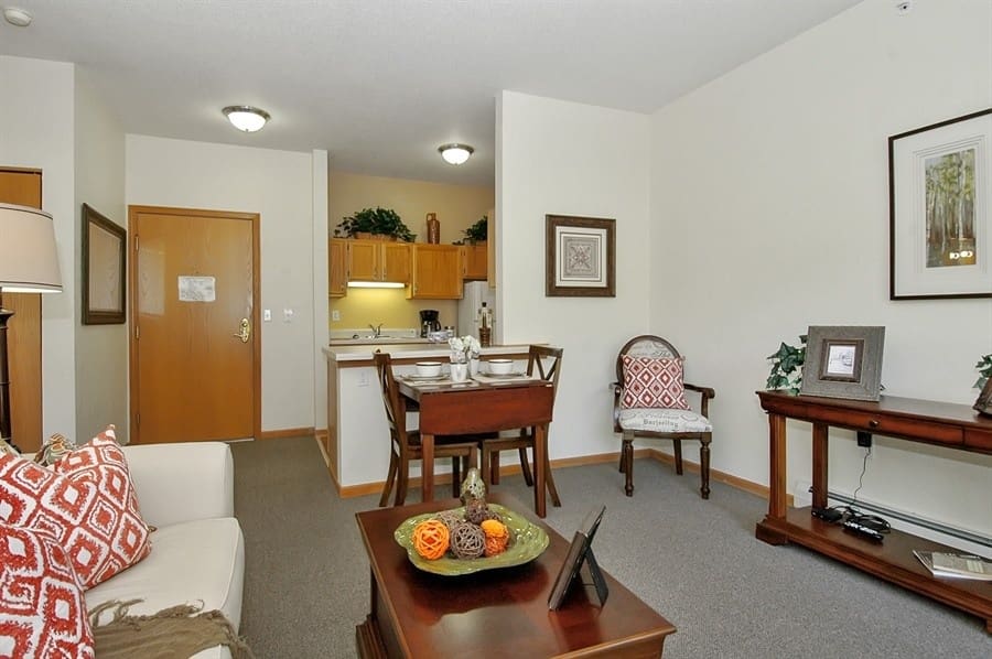 Open-concept living and dining area in assisted living apartment at Charter Senior Living of Madison, WI, featuring cozy seating and full kitchenette