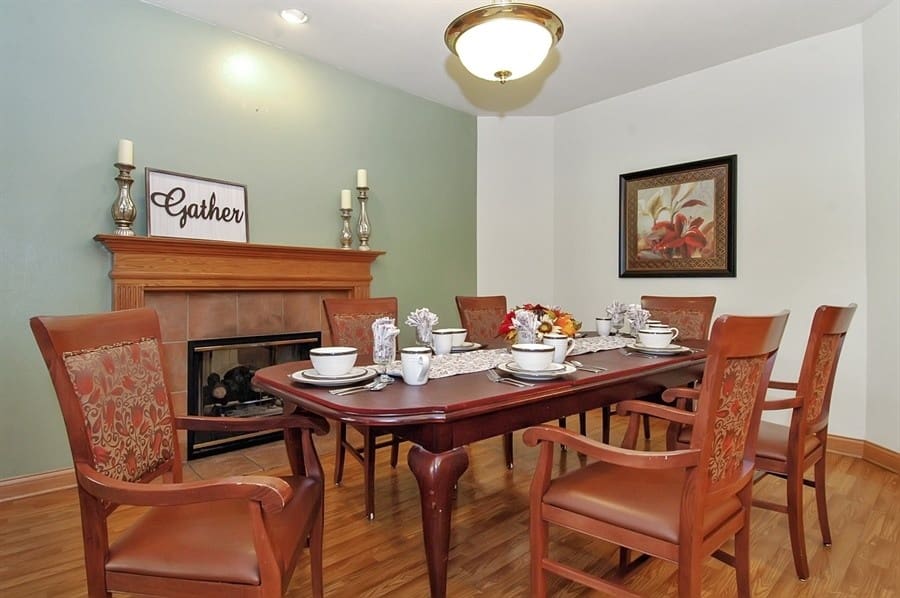 Private dining room at Charter Senior Living of Madison, WI, set for a shared meal with elegant tableware and cozy fireplace.