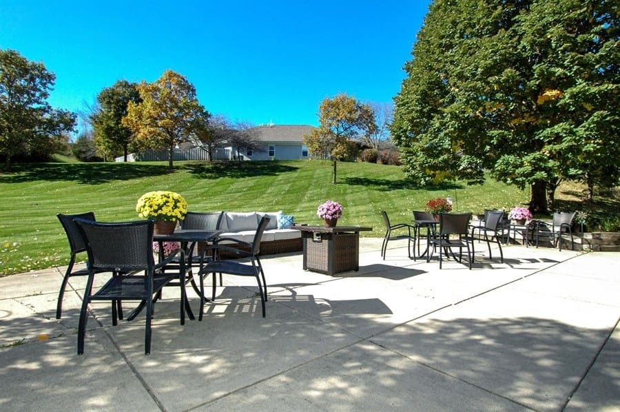 Beautiful outdoor patio with seating and flower arrangements at Charter Senior Living of Madison, WI, overlooking landscaped green space.
